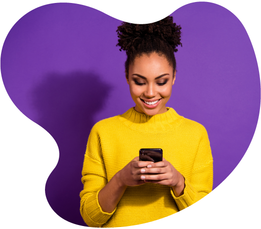 Smiling woman in a yellow sweater using a smartphone against a purple background, showcasing modern digital interaction.